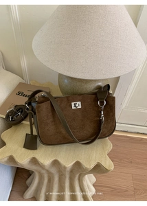 Detail of vintage brown suede shoulder bag with silver twist lock on wooden stool