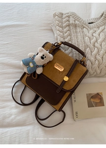 Detail of vintage leather backpack showing dual texture contrast and plush bear accessory