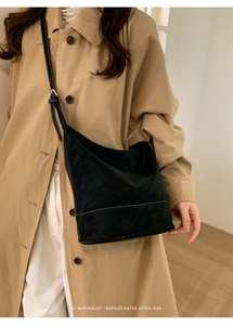 Detail of adjustable strap and white stitching on a black matte faux leather crossbody bag