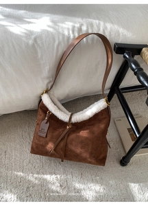 Detailed close-up of brown suede bag with white faux fur trim and geometric embossing