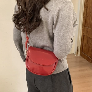 Detail of red leather saddle bag with L.P.W embossed logo and knotted strap detail