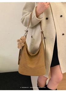 Detailed view of camel hobo bag on shoulder with detachable plush bear charm