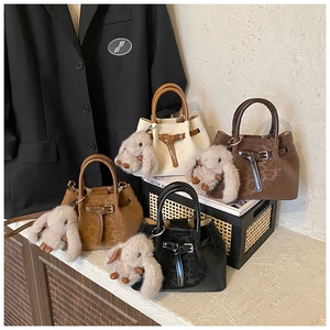 Detail view of retro bucket bags in four colors with plush bunny charms and animal texture
