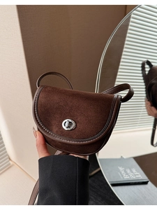 Detail of dark brown saddle bag with suede flap, smooth leather and silver round metal buckle