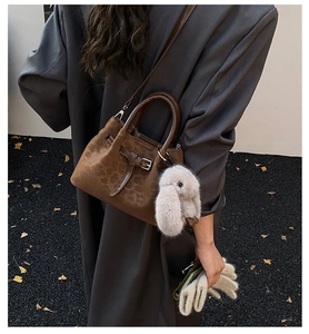 Chic leopard print handbag with plush bunny charm shown against a stylish grey blazer coat