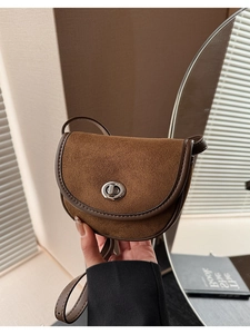Detailed view of brown suede saddle bag featuring silver twist lock and retro leather trim