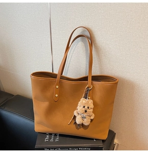 Detail der karamellfarbenen Leder-Tote-Bag mit schmalen Riemen und Plüsch-Hundeanhänger