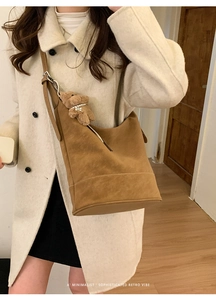 Detail showing brown suede shoulder bag with adjustable strap and cute teddy bear charm