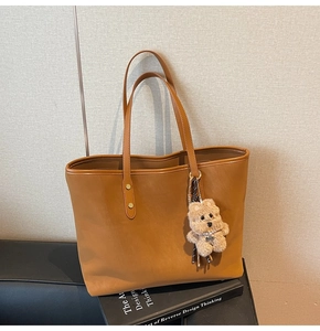 Braune Leder-Shopper mit Reißverschluss und süßem Plüschbär-Anhänger auf Sitz