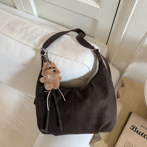 Detail of retro dark brown hobo bag in matte leather with a cute topdog plush pendant