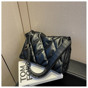 Detail view of black quilted shoulder bag with puffy diamond stitching and gold buckle