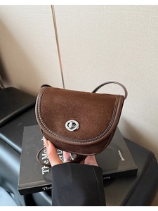 Detail of dark brown suede saddle bag with vintage silver twist lock and leather strap