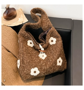 Detail of plush tote bag showing flower embroidery and amber horn button closure
