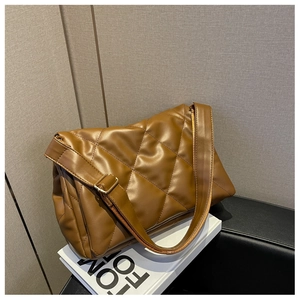 Detail of brown quilted faux leather tote with adjustable strap and gold metal hardware
