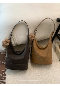 Detail of two retro suede hobo bags in coffee and caramel with cute plush bear charms