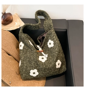 Detail of dark green plush tote bag with white flower embroidery and horn button closure
