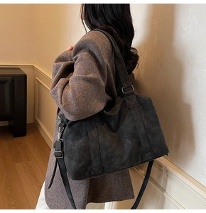 Detail view of large charcoal gray tote bag featuring adjustable crossbody strap and metal ring