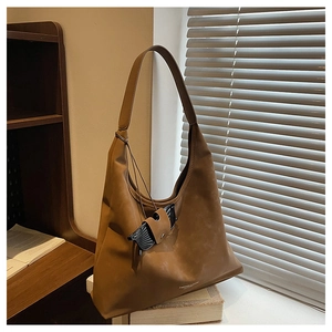 Gros plan du sac porté épaule en cuir mat marron sur des livres avec ombre et lumière