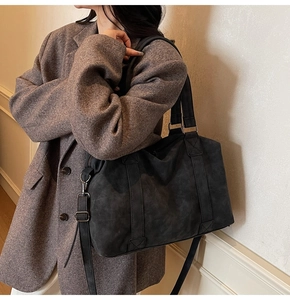Detail of a large dark grey tote bag with dual handles and a detachable shoulder strap