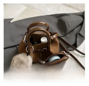 Detail view of brown pleated tote bag interior capacity with a small pouch and plush charm