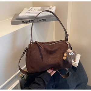 Detail of dark brown frosted suede shoulder bag with a cute fuzzy eye bag charm