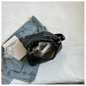 Interior view of black quilted tote bag showing lining, zipper pocket and gold hardware