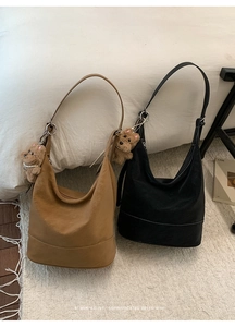 Detail of hobo bucket bags in brown and black leather with cute teddy bear pendants