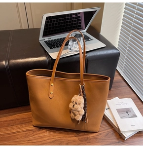 Braune Shopper Tasche aus Leder mit Plüschbär-Anhänger in gemütlicher Büro-Atmosphäre