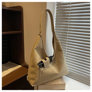 Détail du sac hobo kaki avec clip pour lunettes et logo gravé sur un bureau en bois