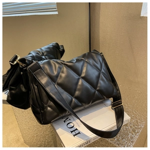 Detail view of black quilted shoulder bag with diamond pattern and gold buckle
