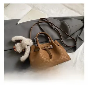 Detail of vintage brown bucket bag with embossed texture and cute rabbit charm