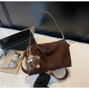 Detail of dark brown matte leather handbag with plush monster eye charm and shoulder strap