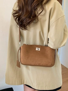 Chic brown suede underarm bag with silver lock worn with a beige trench coat