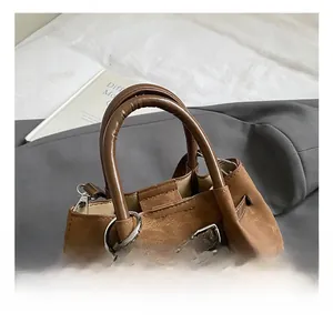 Detail of a brown leather bucket bag with silver lock and a plush grey faux fur ball