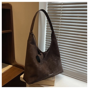 Gros plan détaillé du sac hobo en daim marron foncé avec pendentif et texte de mode chic