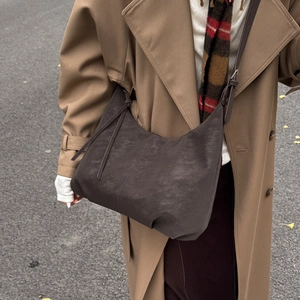 Street style shot of large dark coffee hobo shoulder bag with tassel and adjustable strap