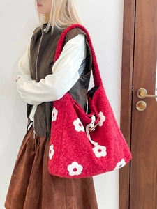 Red plush tote bag with flower embroidery and drawstring toggle closure on shoulder