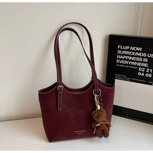 Détail d'un sac cabas bordeaux avec surpiqûres blanches et charme d'ours