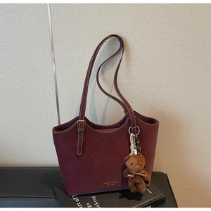 Détail du sac cabas bordeaux en cuir avec logo doré et charm d'ours en peluche