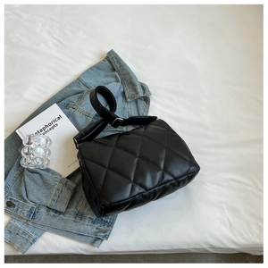 Close-up of black quilted shoulder bag featuring rhombic stitching and wide strap