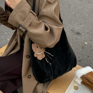 Detail of black leather dumpling bag with cute brown bear charm on khaki coat