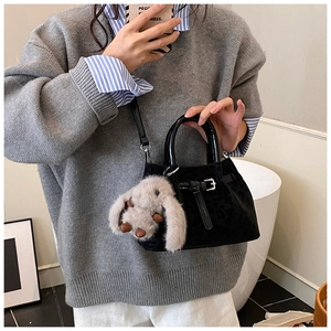 Detail of black velvet leopard pattern bucket bag with plush rabbit charm and silver buckle