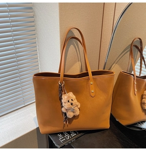 Braune Shopper-Tasche aus Leder mit Bären-Anhänger und Schal in gemütlicher Spiegel-Szene