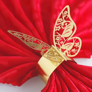 Close-up of golden butterfly napkin ring with laser-cut detail on a red silk napkin