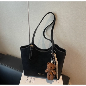 Détail d'un sac cabas noir avec surpiqûres blanches et charmant petit ours en peluche