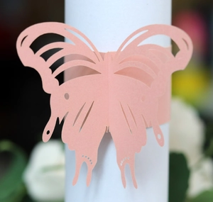 Detailed view of pink laser-cut butterfly paper napkin rings for wedding decor