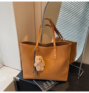 Detail der karamellfarbenen Tote-Bag aus Kunstleder mit süßem Teddybär-Anhänger im Raum