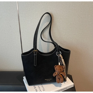 Détail du cabas en cuir noir avec surpiqûres blanches et breloque ours mignonne