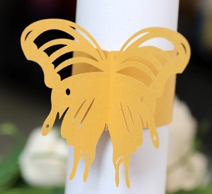 Close-up of golden butterfly paper napkin rings with laser cut hollow design for weddings