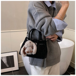 Detail of black suede bucket bag with silver metal hardware and cute white bunny charm